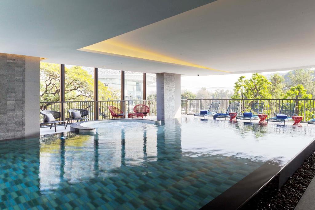 An indoor-outdoor pool beside a bright lounge terrace and tree-lined view.