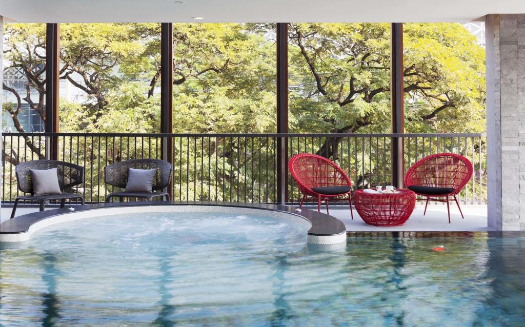 A poolside seating area with a circular spa-like section and views of mature trees.