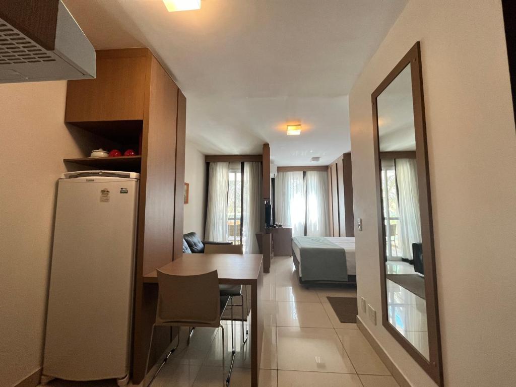 a kitchen and living room with a table and a refrigerator at The Sun Full Condominium Resort in Brasília