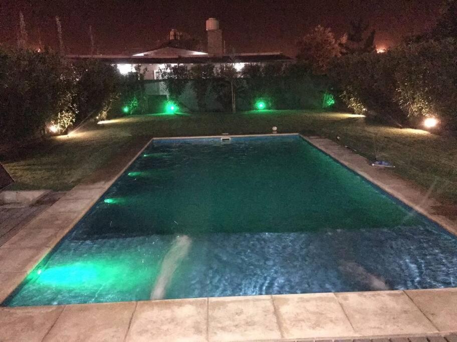 una piscina vacía por la noche con luces verdes en LA CASITA en Roldán