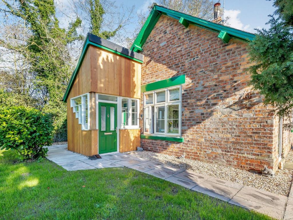 uma casa de tijolos com uma porta verde no quintal em Brickyard Cottage em Metheringham