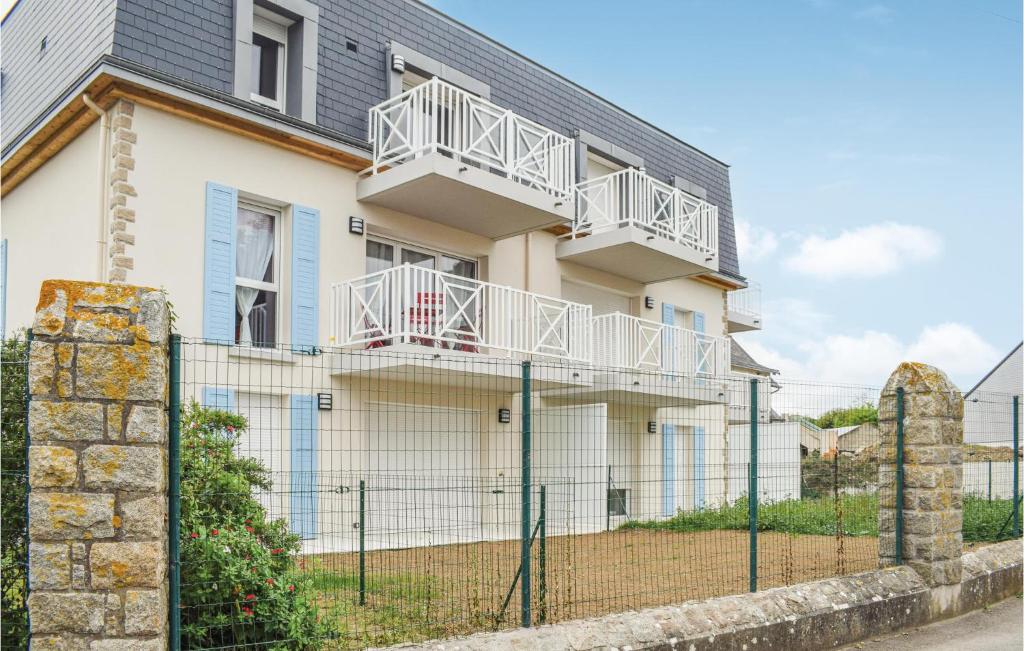 a white house with a fence in front of it at Stunning Apartment In Saint Quay Portrieux With House Sea View in Saint-Quay-Portrieux