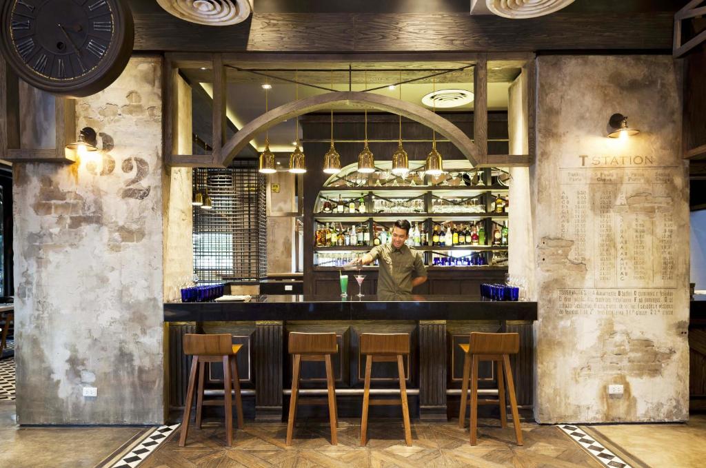 A bar counter with stools, bottle displays and a bartender.