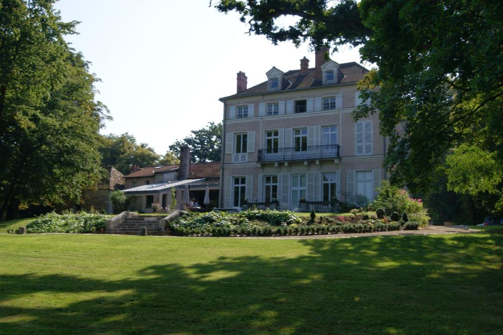 uma grande casa branca com um jardim em frente em Le Chateau De La Vierge em Bures-sur-Yvette