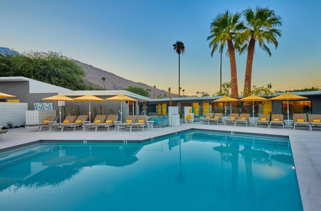a swimming pool with chairs and umbrellas at Twin Palms Resort - Palm Springs Newest Gay Men's Resort in Palm Springs