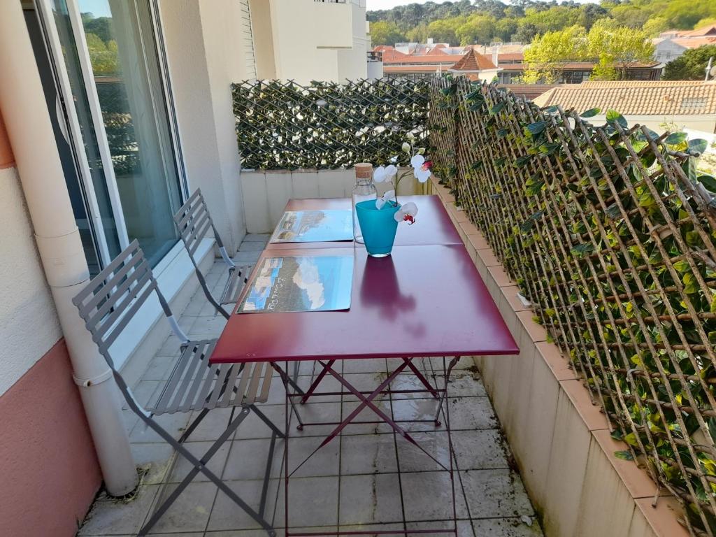 d'une table rouge et de deux chaises sur un balcon. dans l'établissement Arcachon Centre - T2 avec Parking Privé - Ménage Inclus - FR-1-319-463, à Arcachon