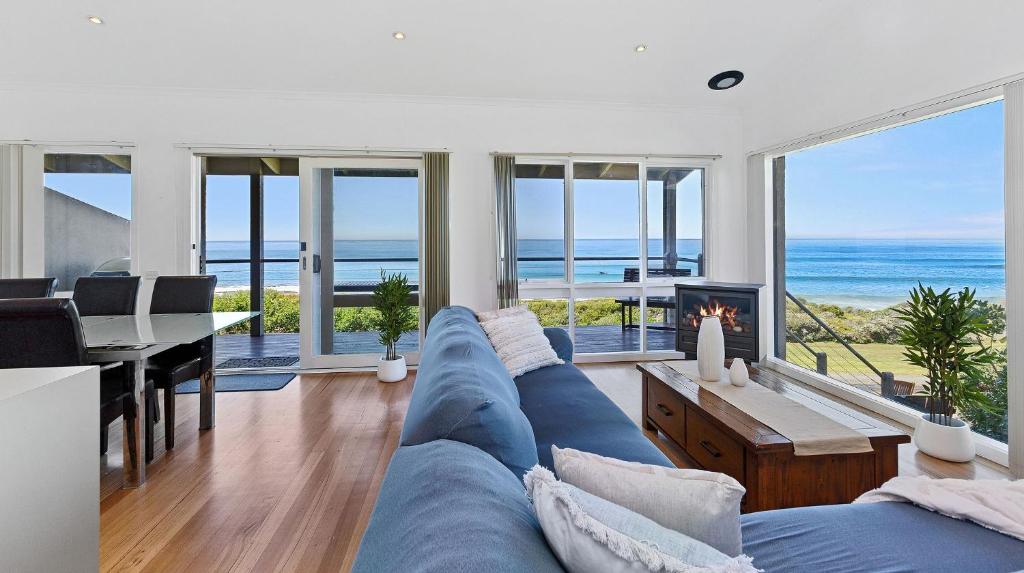 a living room with a blue couch and a view of the ocean at Whitecrest Eco Apartments Great Ocean Road in Apollo Bay