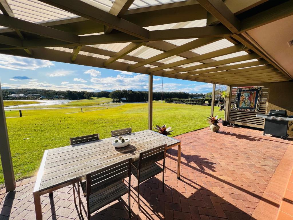 a picnic table on a patio with a view of a field at Perfect weekend getaway plus golf at your doorstep in Salamander Bay