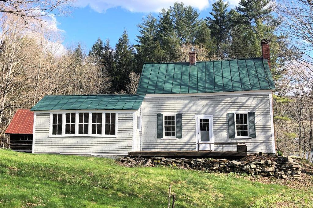una casa vieja con techo verde en una colina en Riverside Cottage, en Woodstock