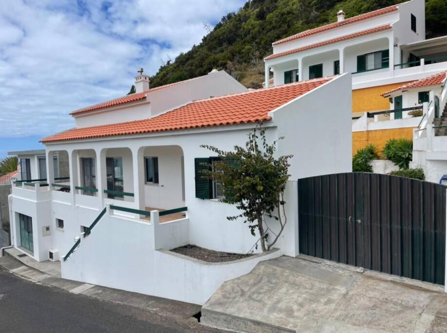 a white house with an orange roof and a fence at Casa de Praia in Almagreira