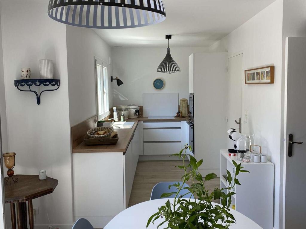 uma cozinha com armários brancos, uma mesa e uma sala de jantar em Maison Bénodet, 4 pièces, 8 personnes - FR-1-481-126 em Bénodet
