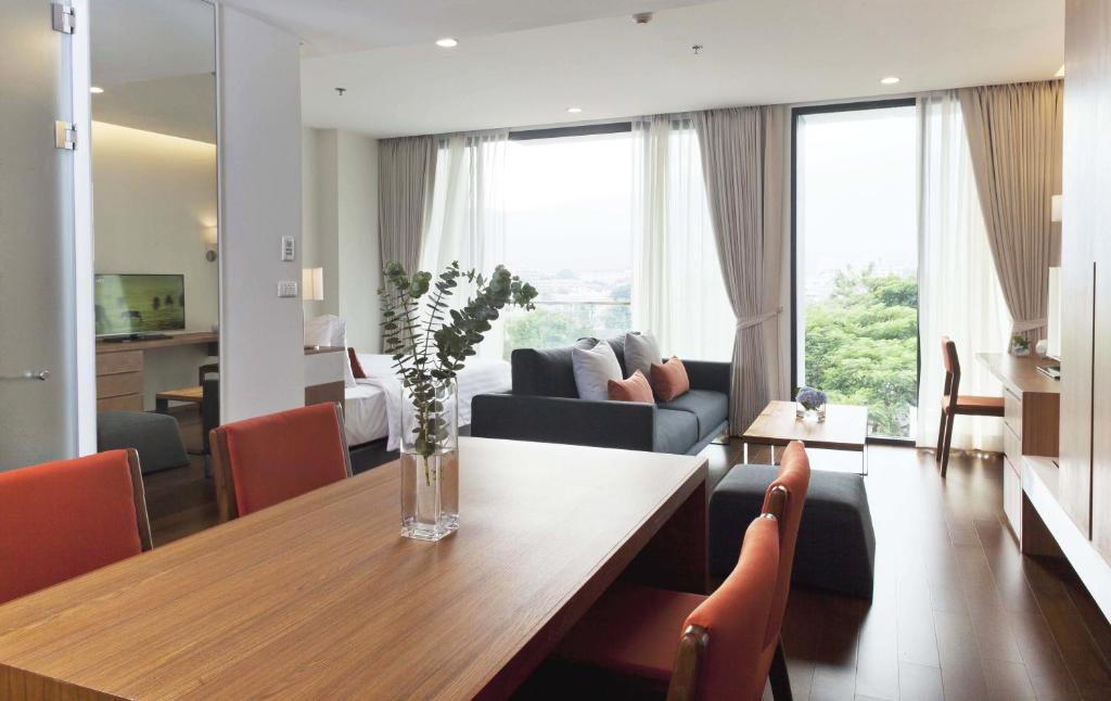 An open-plan suite with a dining table, lounge seating, and large windows.
