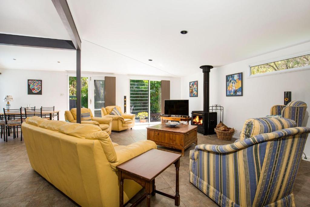 a living room with yellow couches and a tv at Grey Gables Pet Friendly with Swimming Pool and Spa in Callala Bay