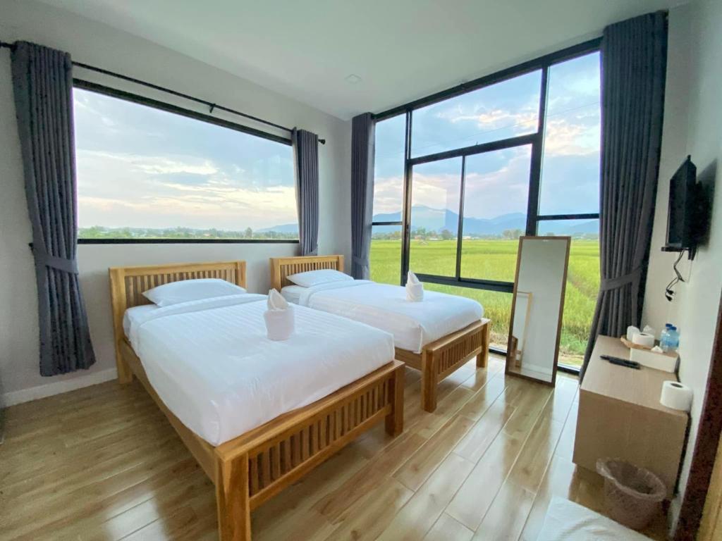 two beds in a room with large windows at เดอนาปัว วิลล่า in Ban Chalaeng