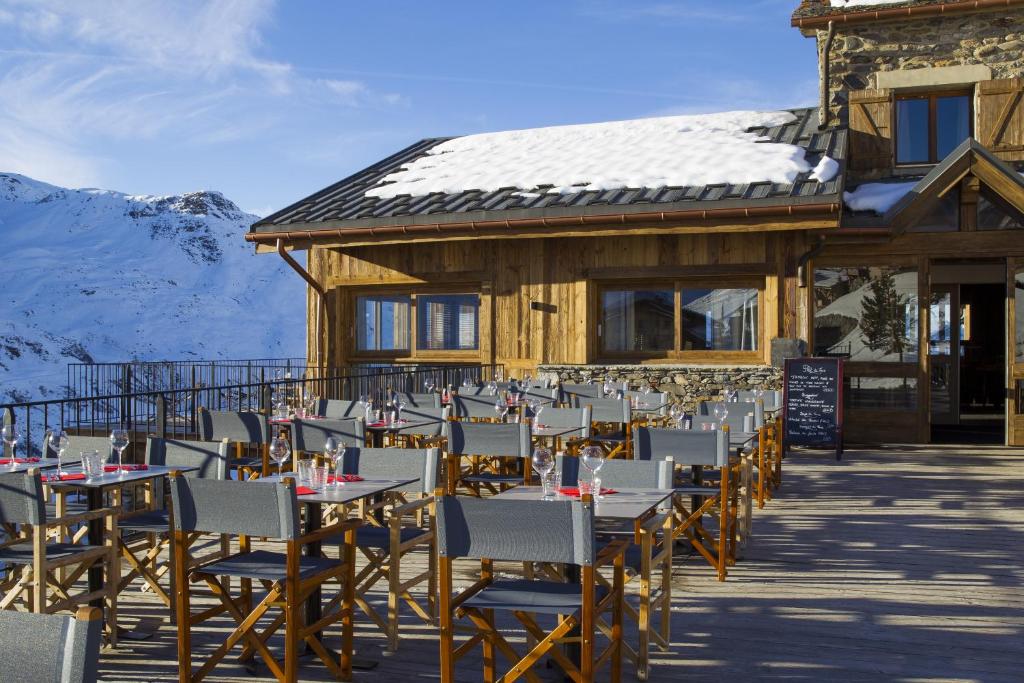 a group of tables and chairs in front of a building at Hillary Hotel in Les Menuires