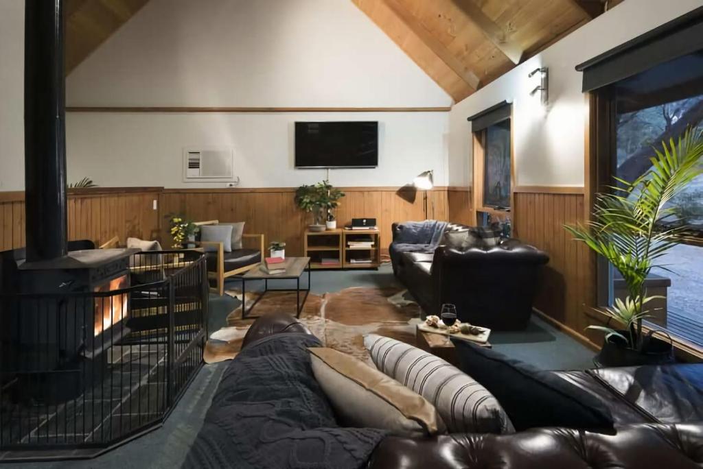 a living room with leather furniture and a flat screen tv at The Lodge Daylesford in Hepburn