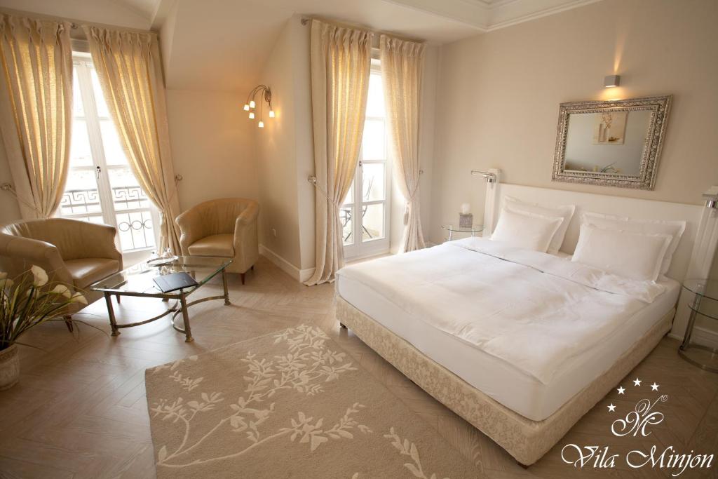 a bedroom with a white bed and a table and chairs at Luxury Rooms Minjon in Vrnjačka Banja
