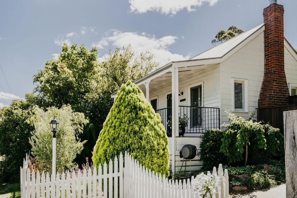 a white picket fence in front of a white house at Candlebark Daylesford in Daylesford