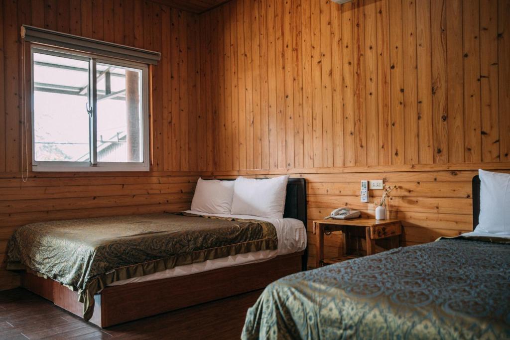 Duas camas num quarto com paredes de madeira e uma janela em CDR Hotspring Resort em Liugui