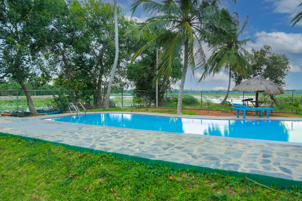 a swimming pool in a resort with a table and a bench at Lake Edge Holiday Inn in Tissamaharama