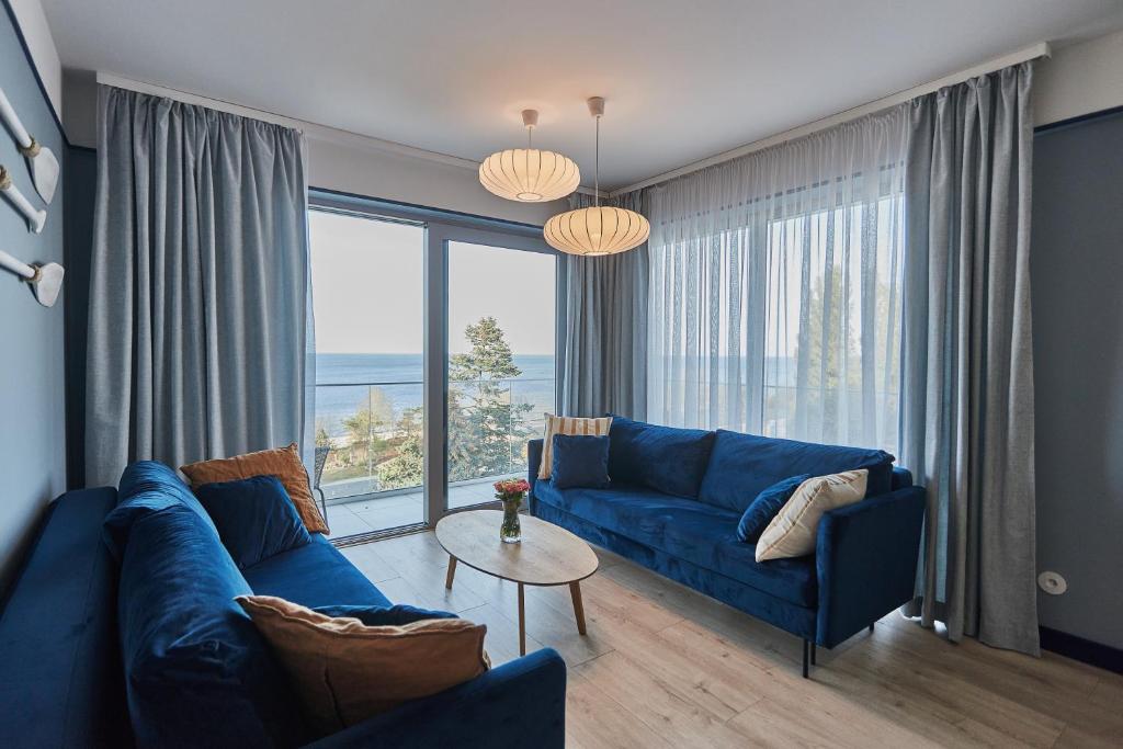 ein Wohnzimmer mit einem blauen Sofa und einem großen Fenster in der Unterkunft Sofia Balticus Check-in in Misdroy