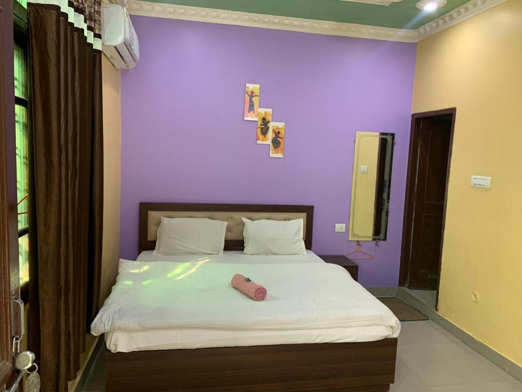 sypialnia z łóżkiem z fioletową ścianą w obiekcie MANIK GUEST HOUSE w mieście Rishikesh
