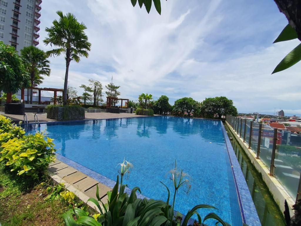 a large blue swimming pool next to the ocean at TripleQ Room 2BR Vidaview Apartment in Makassar