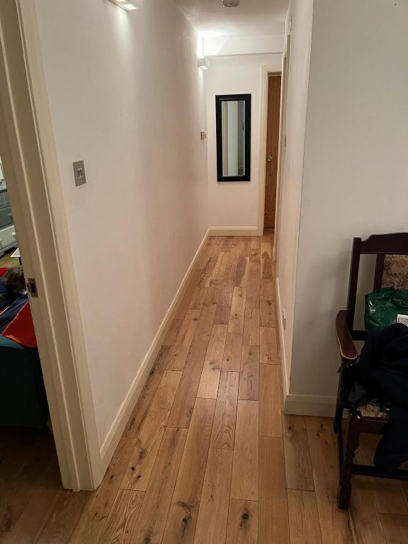 a hallway with a hard wood floor and a mirror at Chiswick two minutes station home in London