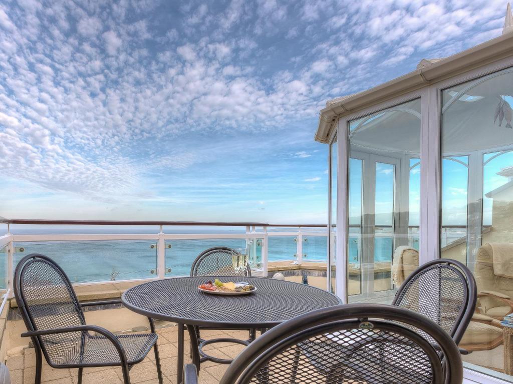 una mesa y sillas en un balcón con vistas al océano en Laurellie en Carbis Bay