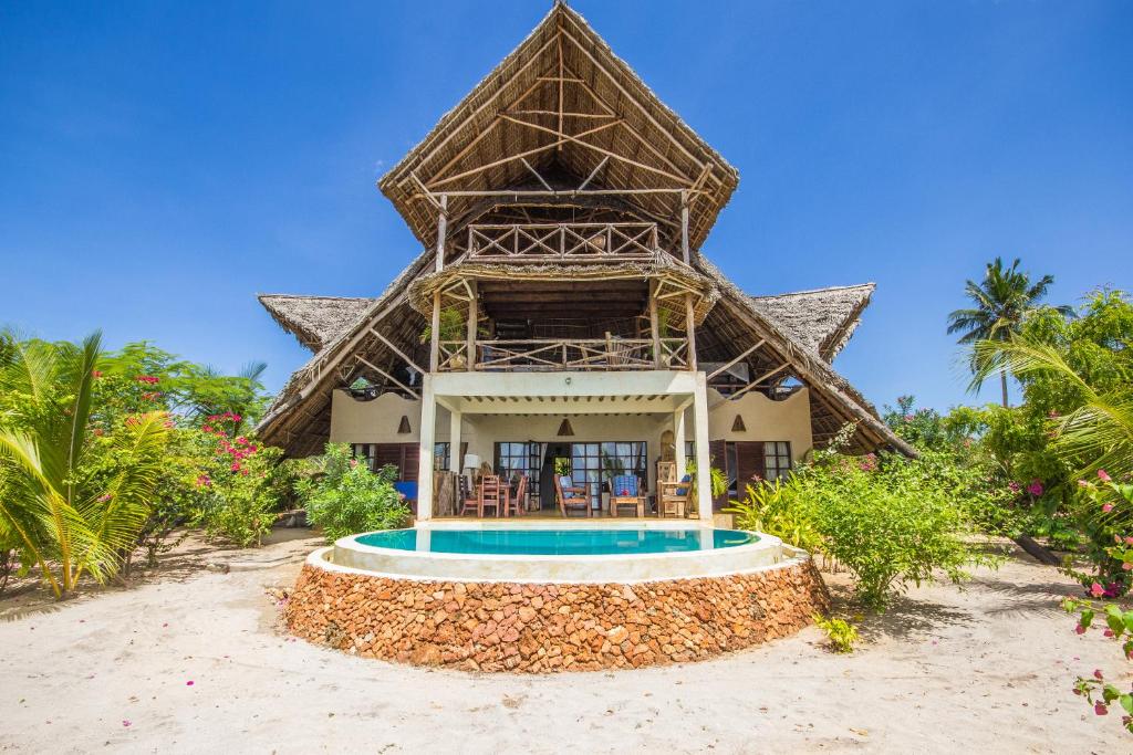 a resort with a swimming pool in front of a building at Milele Villas in Potoa