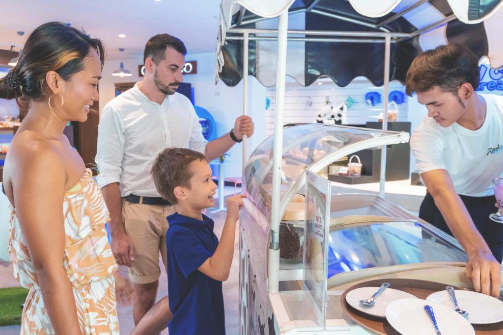 eine Gruppe von Menschen, die ein Spielzeugauto ansehen in der Unterkunft Radisson Resort and Suites Phuket in Kamala Beach