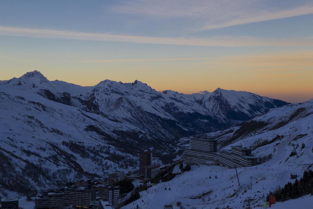 a city in the snow with mountains in the background at Hillary Hotel in Les Menuires