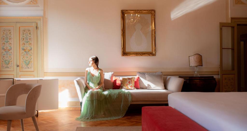 une femme assise sur un canapé dans un salon dans l'établissement Palazzo Maria Formosa, à Venise