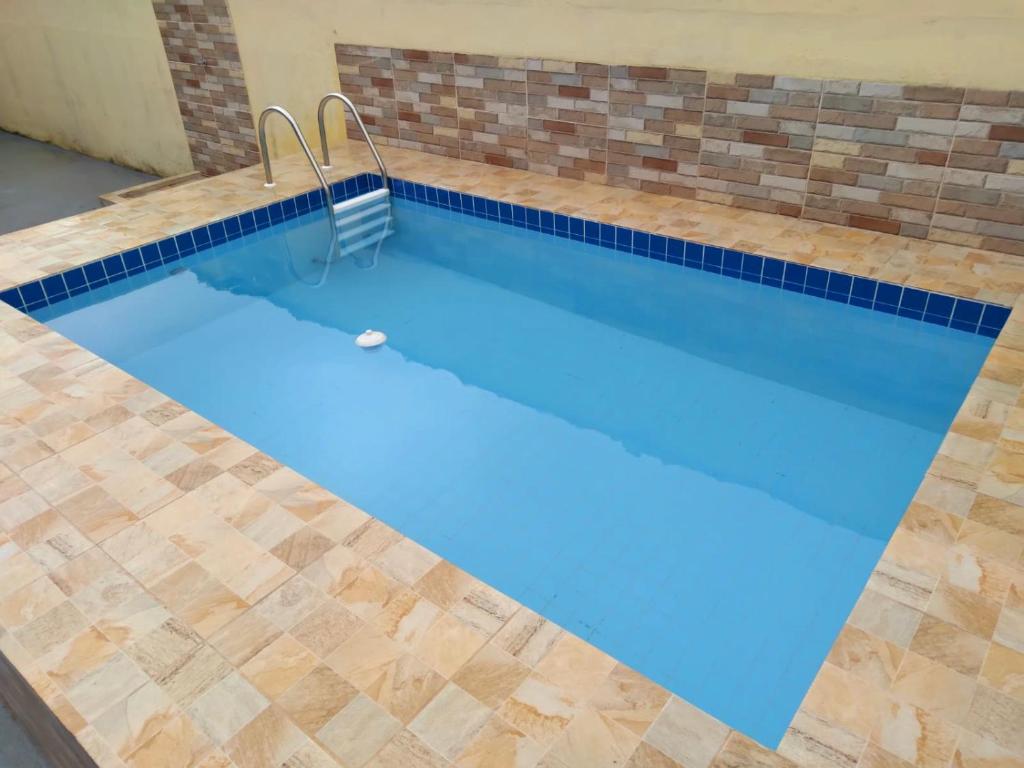 uma grande piscina com uma parede de tijolos e azulejos azuis em Casa em Condomínio com Piscina Privativa em Araruama