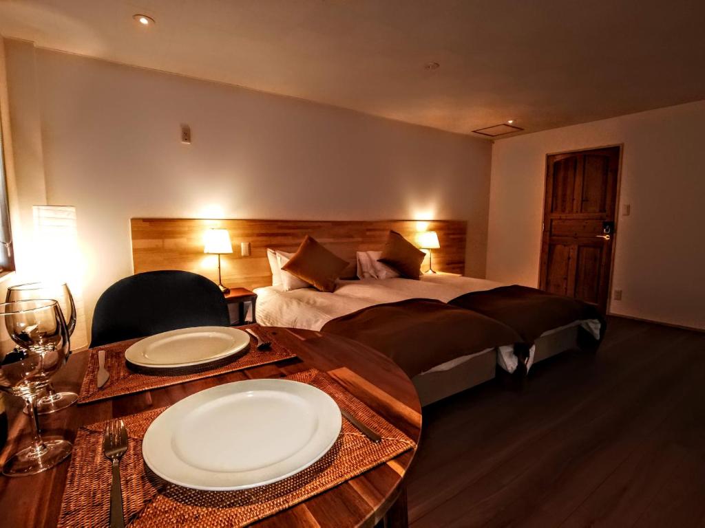 una habitación de hotel con una cama y una mesa con platos. en Fujio Pension Madarao Apartment Hotel & Restaurant en Iiyama