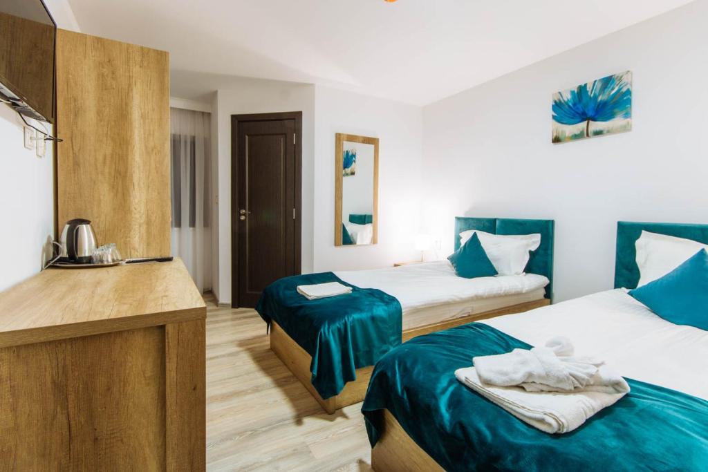 una camera d'albergo con due letti con lenzuola blu di Vila Stadion a Câmpulung Moldovenesc