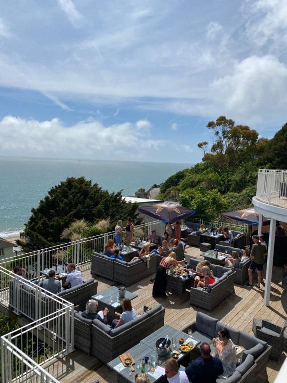 a group of people sitting at tables near the ocean at The Wellington Hotel in Ventnor