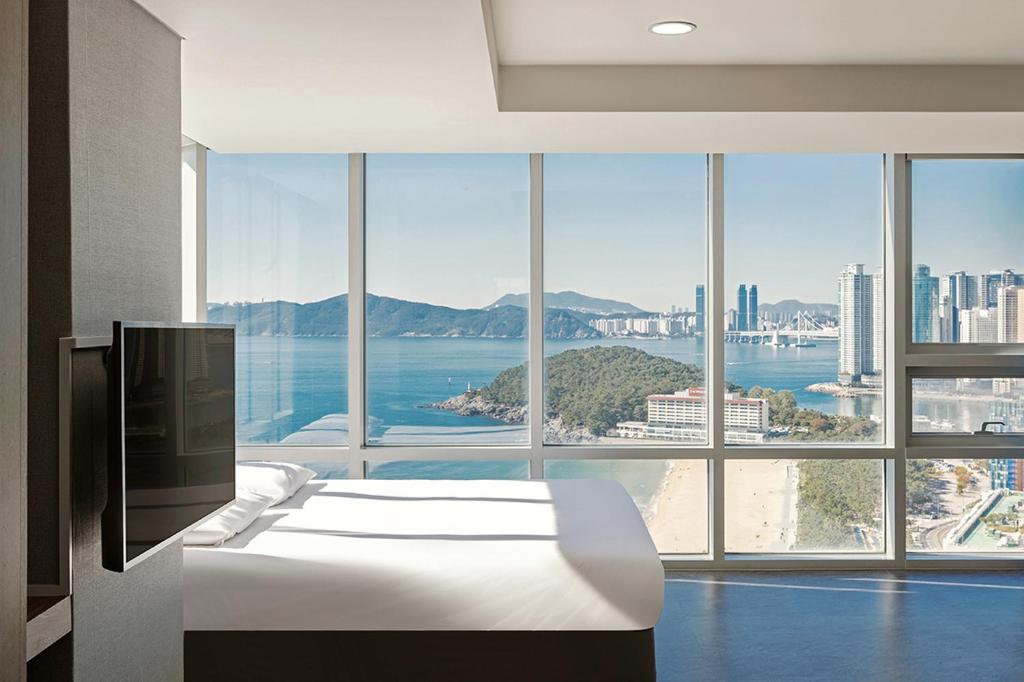 ein Schlafzimmer mit einem weißen Bett und einem großen Fenster in der Unterkunft Sun Cloud Hotel in Busan