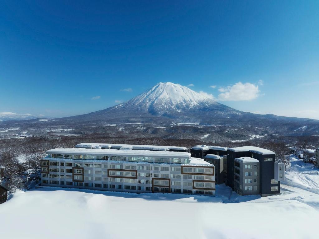 un bâtiment dans la neige avec une montagne en arrière-plan dans l'établissement Setsu Niseko, à Niseko