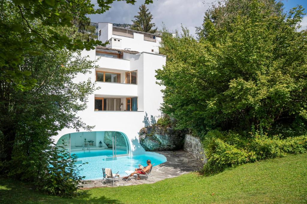 una pareja sentada frente a una casa con piscina en Casa Las Caglias, en Flims