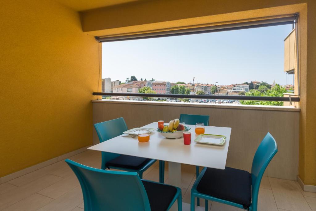 een eetkamer met een tafel en stoelen en een groot raam bij Apartment Mara Premium in Poreč