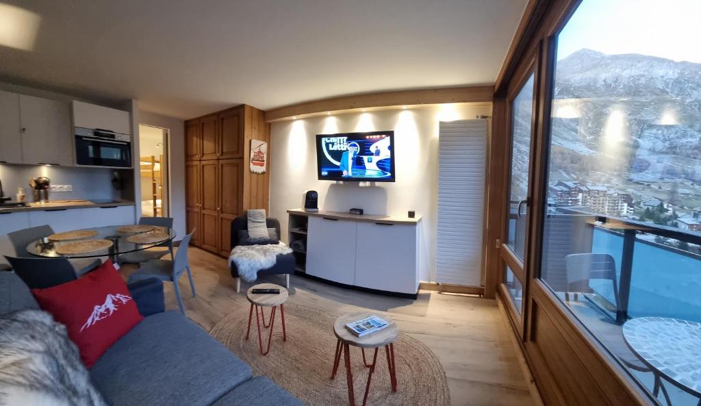 a living room with a couch and a kitchen with a tv at Le 1888 Val d'Isère in La Daille