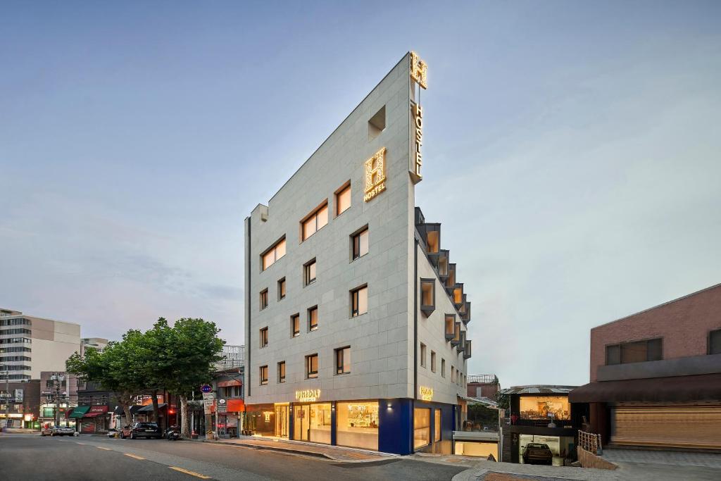 un grand bâtiment blanc sur le côté d'une rue dans l'établissement H HOSTEL Itaewon, à Séoul