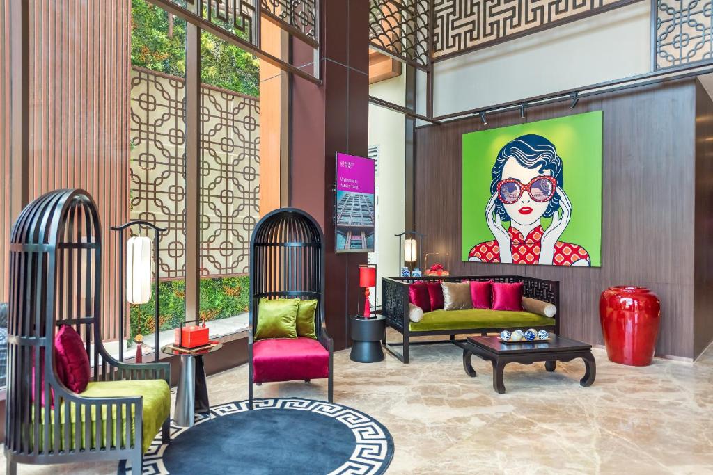 a lobby with chairs and a painting of a woman at Ashley Tang Menteng Jakarta in Jakarta