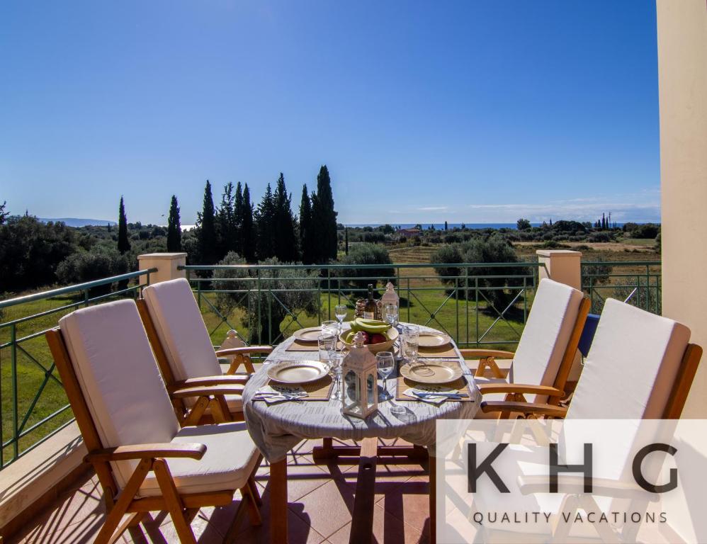 een tafel en stoelen op een balkon met uitzicht bij Villa Elaionas 1 Experiencing nature's tranquility! in Svoronata