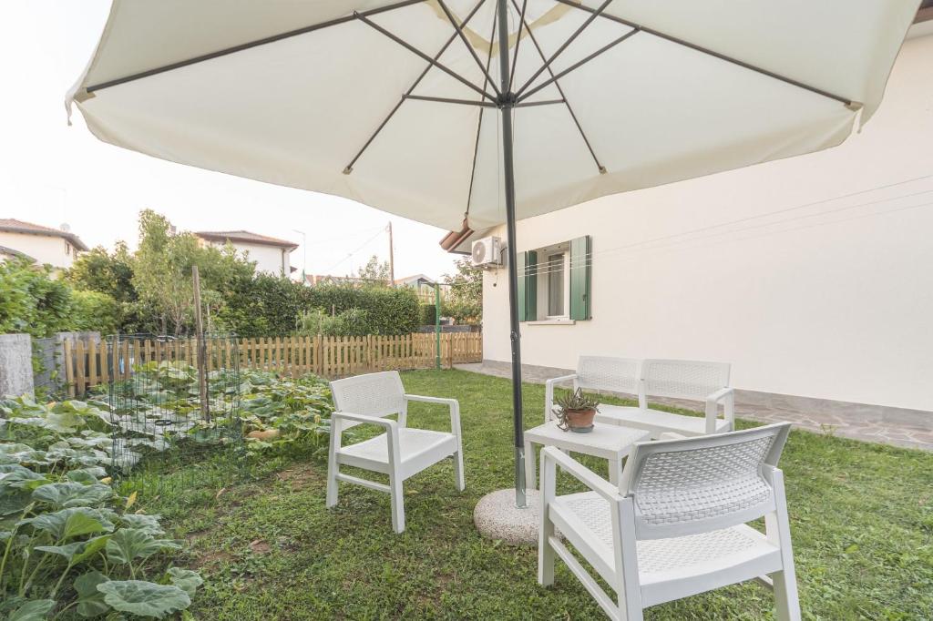 einen weißen Terrassentisch und Stühle unter einem Sonnenschirm in der Unterkunft Da Nonna Antonia in Martellago