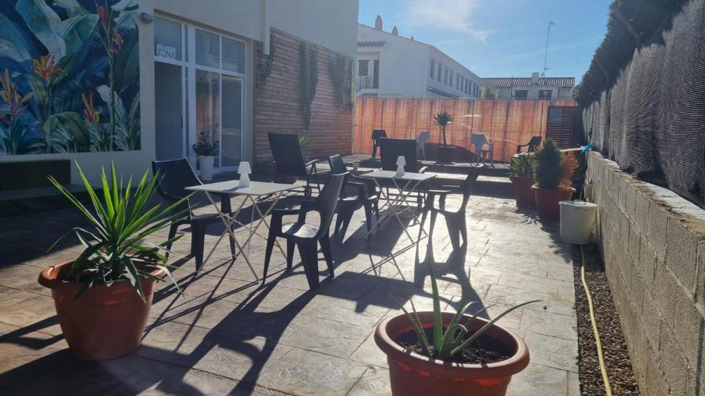 a patio with tables and chairs and potted plants at Zona5 Apartamentos Turísticos in El Vendrell