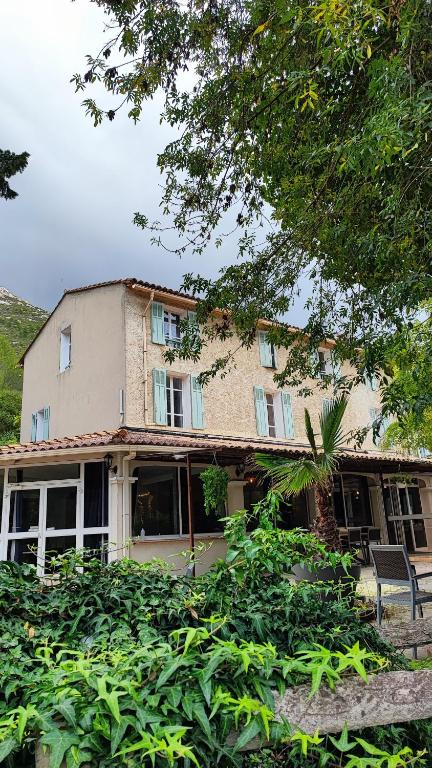 Una casa vieja con muchos arbustos delante. en Logis Hôtel &amp; Restaurant du Parc, en Gémenos