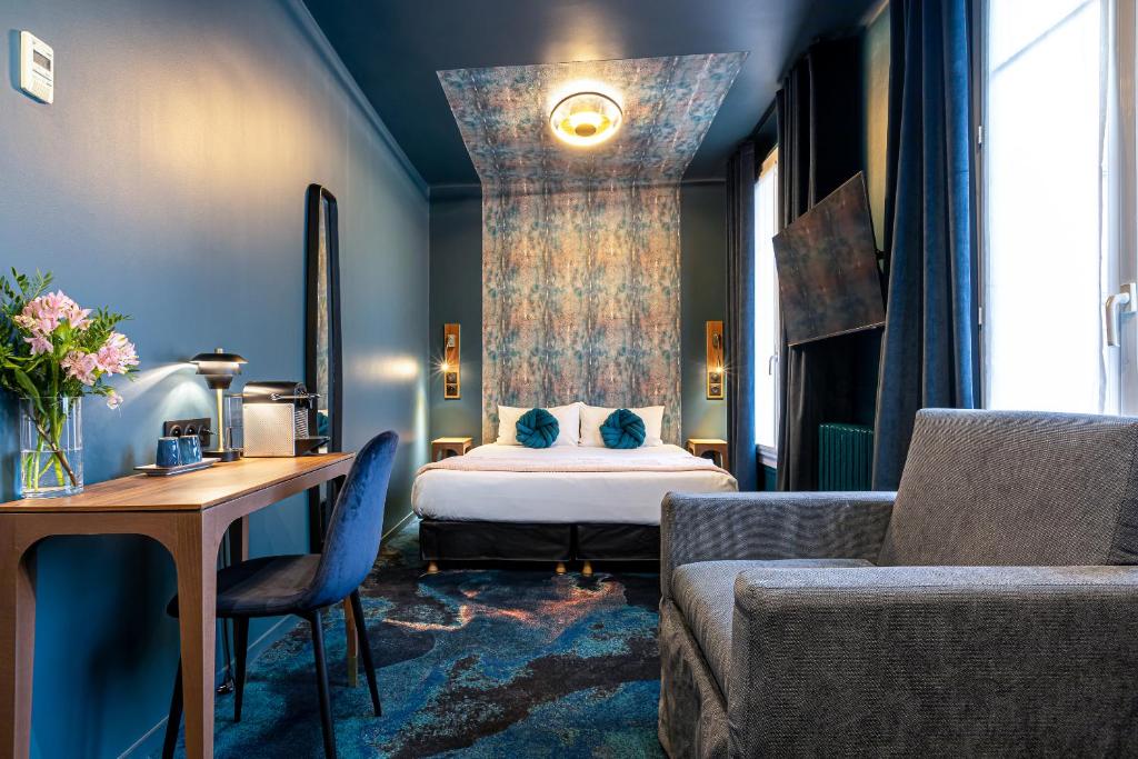 a bedroom with a bed and a table and a couch at Hotel Glasgow Monceau by Patrick Hayat in Paris