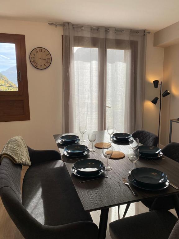 a dining room table with chairs and a clock on the wall at Appartement Le Lauzet in La Roche-de-Rame